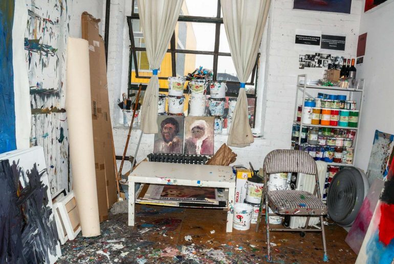 a messy room with a painting on the wall