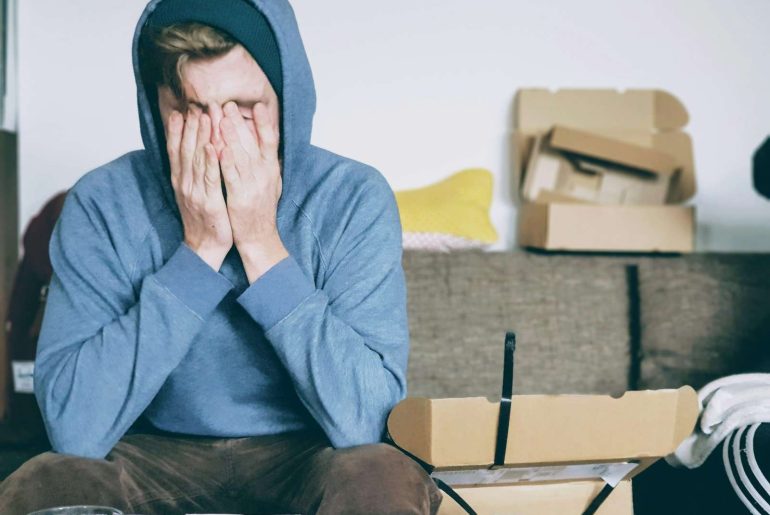 man covering face with both hands while sitting on bench